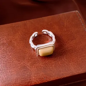Detailed view of a silver geometric open ring with a yellow rectangular resin stone