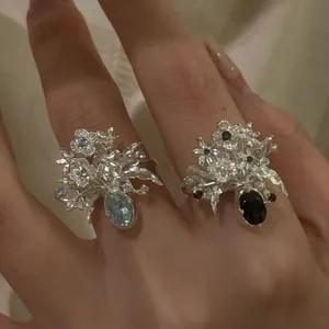 Close-up detail of two sweet floral zircon rings featuring blue and black center stones