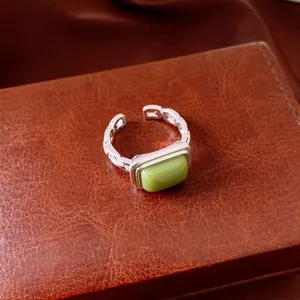 Close-up view of a green square resin geometric open ring on a brown leather texture