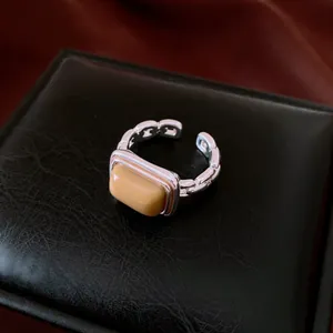 Detailed view of square yellow resin stone on silver-toned geometric open ring