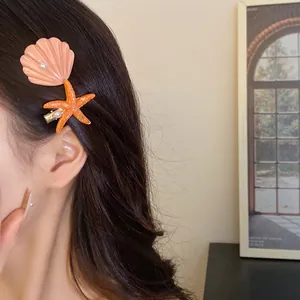 Close-up detail of starfish and seashell hair clips with white pearls on dark hair