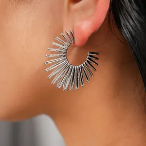 Close-up of silver sunburst C-shaped metallic earring with vintage spiky textured design
