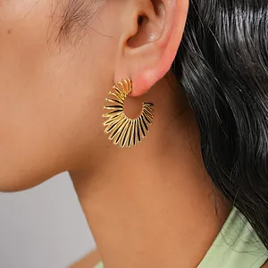 Close-up of vintage gold C-shaped metal earrings with textured sunburst design.