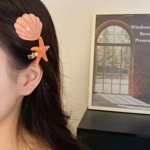 Detail view of a woman wearing decorative seashell and starfish hair clips with pearls