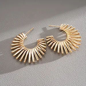Detailed macro shot of vintage gold C-shaped sunburst earrings with a textured metallic finish