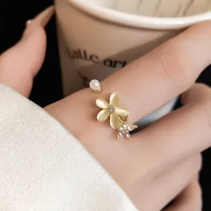 Elegante anello aperto con fiore in occhio di gatto, strass e perla sul dito.