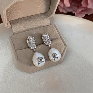 Elegant vintage style silver rose pearl drop earrings shown in a luxury jewelry box