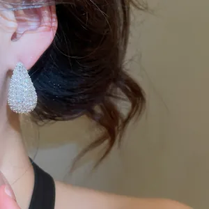 Close-up detail of elegant teardrop-shaped zircon pavé earrings worn on a model's ear for style