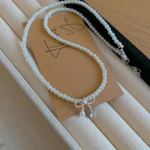 Nahaufnahme einer eleganten Perlenkette mit silbernem Schleifenanhänger und Kristall
