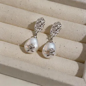 Macro detail of elegant retro earrings featuring hammered metal and rose-adorned pearls.
