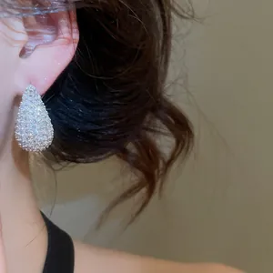 Close-up macro detail of sparkling teardrop-shaped cubic zirconia paved earrings for women
