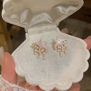 Detailed view of sparkling star earrings with rhinestones in a shell jewelry box