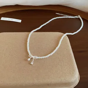 Detailaufnahme der eleganten Perlenkette mit zarter Schleife und Kristallanhänger.
