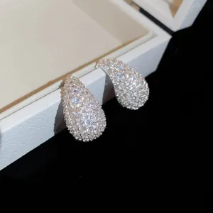 A close-up view of sparkling teardrop-shaped zircon stud earrings in a white gift box