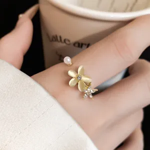 Primo piano di un elegante anello aperto con fiore occhio di gatto e dettagli in zircone.
