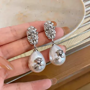 Close-up of elegant vintage pearl drop earrings with rose and pleated silver metal