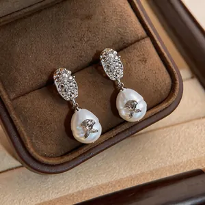 Close-up detail of vintage pearl drop earrings with intricate silver rose flower accents
