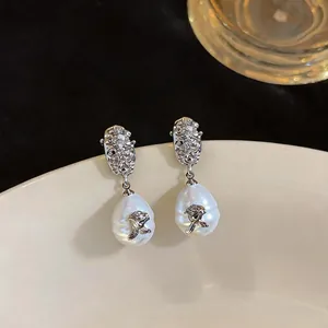 Detail macro view of vintage silver earrings with pearl drops and rose ornaments.