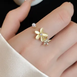 Primo piano di anello regolabile dorato con fiore in pietra occhio di gatto e strass lucenti