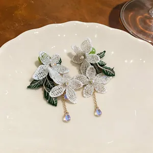 Detailed view of lace flower earrings with pearls and iridescent water-drop pendants