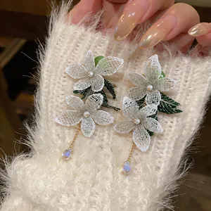 Close-up of elegant white mesh floral earrings featuring pearls and crystal teardrops