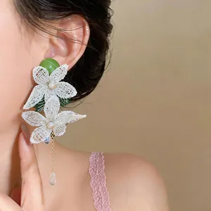 Detailed close-up of elegant white mesh flower earrings with pearls and teardrop crystals
