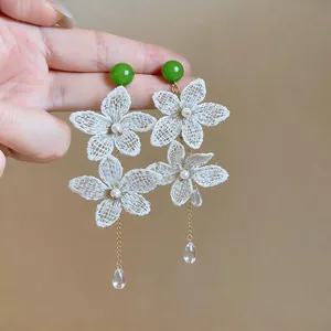 Detail view of handmade lace flower earrings with green beads and pearl accents