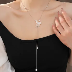 Elegant detail view of a silver-toned hollow bow necklace with white pearls on a model