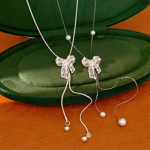 Detailed view of silver hollow bow necklace with pearls and elegant snake chain