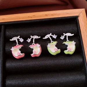 Detailed view of enamel apple stud earrings with shimmering zircons and silver posts.