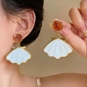 Close-up detail view of elegant beach vacation style shell pendant earrings for women