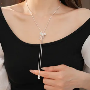 Detailed view of a silver hollow bow pendant on an adjustable silver clavicle chain