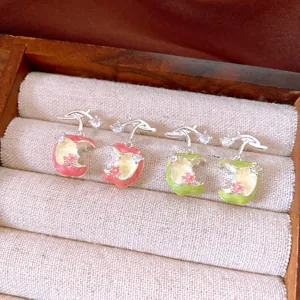 Detailed macro view of dainty zircon enamel apple stud earrings in red and green