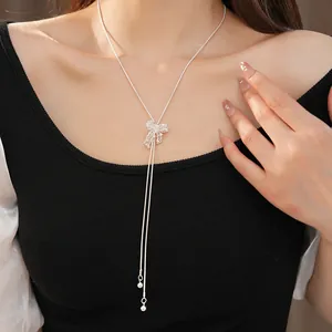 Close-up shot of an elegant silver hollow bow-knot necklace worn by a fashion model.