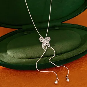 Detailed view of a silver hollow-out bow-knot necklace with an adjustable chain.
