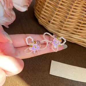 Close-up of colorful Y2K style handmade beaded earrings with purple flowers and pearls