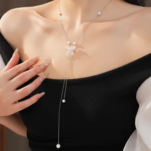 Close-up view of an elegant silver hollow bow necklace with white pearls worn by a model