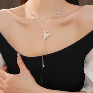 Exquisite detail view of a silver hollow bow necklace featuring delicate pearls on a model