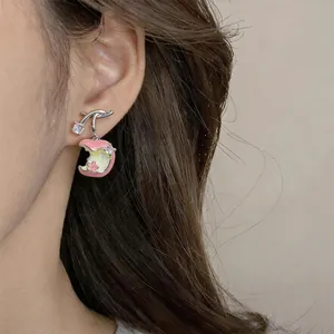 Close-up of pink enamel apple earrings with zircon on a model's ear