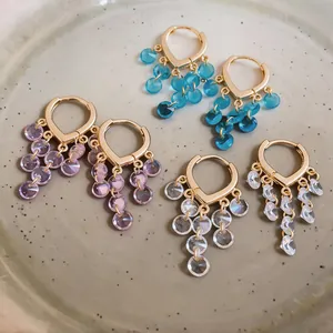 Detailansicht eleganter goldfarbener Creolen mit facettierten Glasperlen-Anhängern.