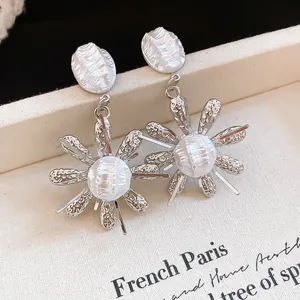 Detail shot of French retro earrings with wrinkled pearl petals and silver flower base.