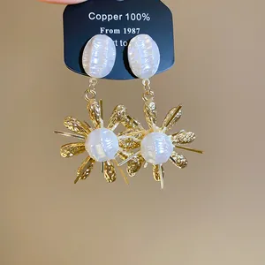 Detailed macro view of French vintage gold flower earrings with pearl-like accents.