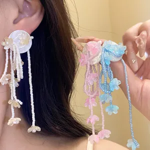 Detailed close-up of sweet resin flower tassel earrings in white, pink and blue colors.