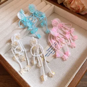 Close-up detail of sweet resin flower tassel earrings in pastel blue, pink and white