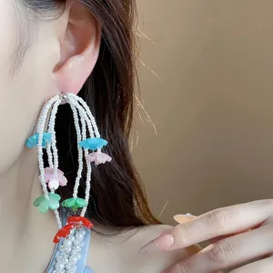 Bohemian multi-color resin flower tassel earrings with white beads worn on ear
