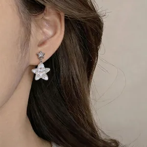 Exquisite star-shaped mother-of-pearl stud earrings with tiny rhinestones on a model