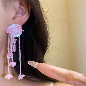 Detailed macro view of pink resin flower tassel earrings with elegant beaded fringes