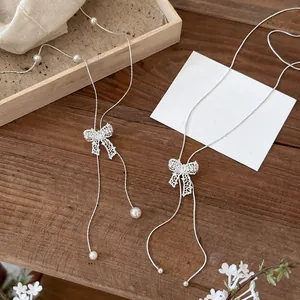 Close-up of delicate zircon hollow bow pendants on silver adjustable lariat necklaces