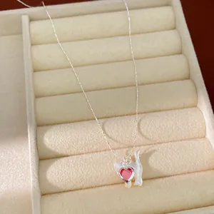 Dettaglio di una collana con ciondolo a gatto e gemma rossa a forma di cuore