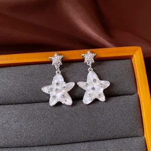 Macro view of silver star earrings featuring mother-of-pearl inlay and rhinestones.